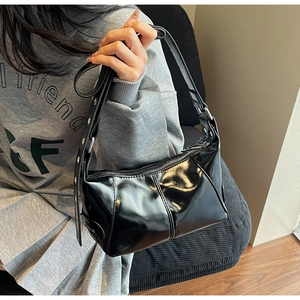 Dettaglio borsa in pelle lucida nera con occhielli argento e chiusura a zip