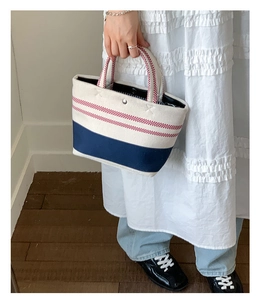 Close-up of canvas tote bag with red stripes, dark blue bottom, and metal snap button