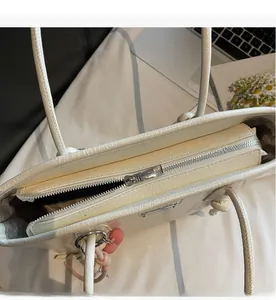 Close-up of smooth silver zipper closure on white crocodile embossed leather tote bag