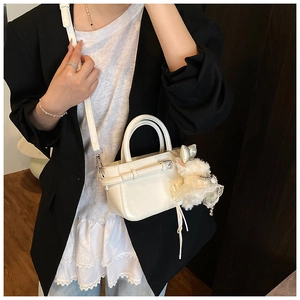Gros plan du mini sac seau blanc brillant avec un charme décoratif en peluche douce