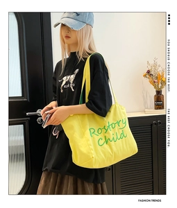 Modèle portant un grand sac fourre-tout en toile jaune avec broderie verte sur le côté