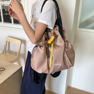 Detail of khaki nylon tote bag with drawstring, fashion label and dog plush pendant