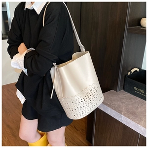 Schicke cremefarbene Leder-Beuteltasche mit Laser-Cut-Details am Model bei sanftem Licht