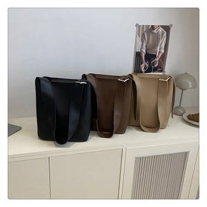 Close-up of minimalist bucket bags in black, brown, and beige with silver buckles
