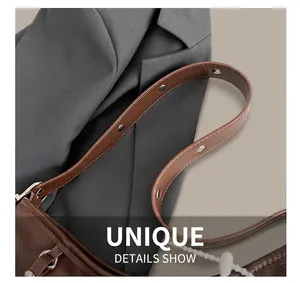 Detail of a brown leather shoulder bag strap with silver circular rivets and metal buckles