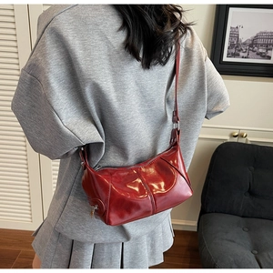 Dettaglio di una borsa a mezzaluna rosso scuro con cerniera argento e trama in pelle