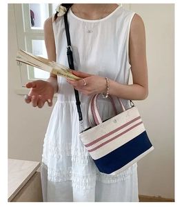 Detail of canvas tote with red stripes and blue patchwork shown on a white dress model