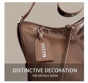 Detail shot of a dark brown leather tote bag with MASHK luggage tag and fine stitching