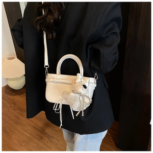 Gros plan du sac seau en cuir verni blanc avec pendentif poupée en peluche et perles