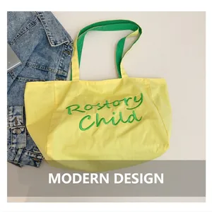 Détail du cabas en toile jaune avec broderie verte et poignées bicolores contrastées