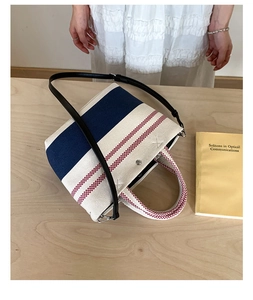 Detail of canvas stripe tote bag on wooden table with blue and red accents