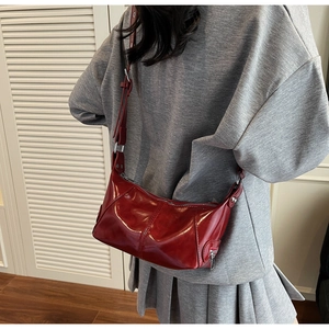 Dettaglio della borsa a tracolla bordeaux in pelle cerata con finiture argentate