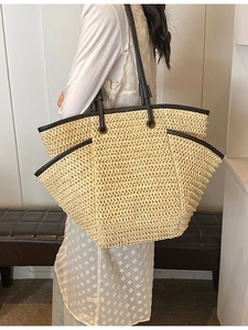 Large beige woven straw tote bag with black synthetic leather handles for summer travel