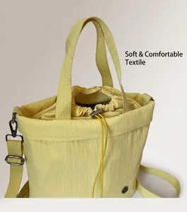 Close-up of light yellow canvas bucket bag with drawstring closure and woven straps