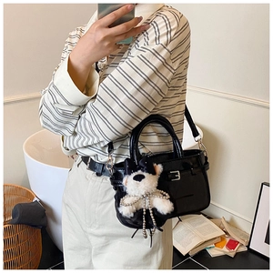 Détail du sac cabas noir brillant avec pendentif ours en peluche blanc et garnitures argentées
