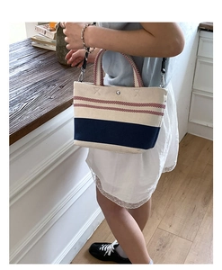 Detail of canvas tote bag showing striped texture and detachable shoulder strap on desk