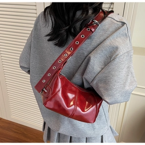 Dettaglio borsa a spalla rosso scuro con ampia tracolla con occhielli metallici e zip