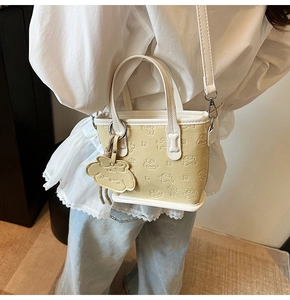 Détail du sac fourre-tout en cuir PU blanc crème avec motifs chiots gaufrés et breloque