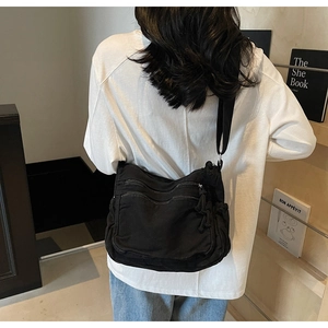 Detail view of a black canvas crossbody bag with multi-zipper pockets for storage