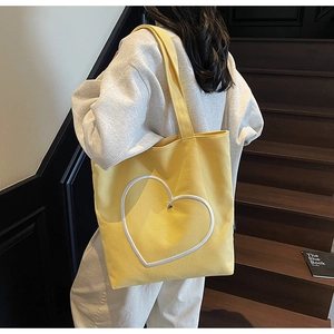 Détail du sac cabas en toile jaune avec broderie cœur blanche et rivet métallique
