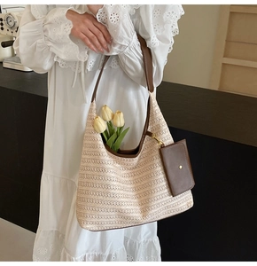 Detail of woven hobo bag with brown leather strap and mini pouch on white lace dress