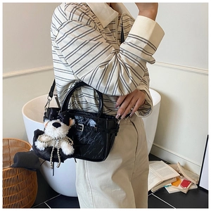 Détail du sac en cuir verni noir avec pendentif chiot et chaîne de perles décorative