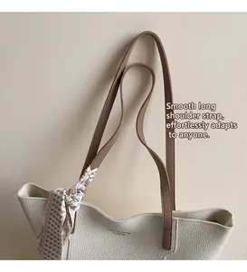 Close-up of white lychee pattern tote bag with brown straps and geometric silk scarf detail