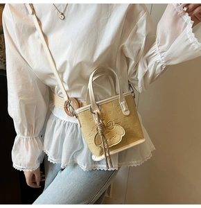 Détail du sac cabas beige en simili cuir avec motifs de chiots gaufrés et breloque déco