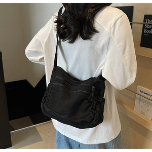 Detail of black canvas tote bag showing double front zipper pockets and durable webbing strap