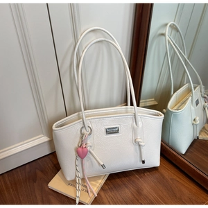 Close-up of white wrinkled leather tote bag with silver logo and pink heart charm