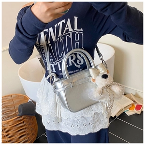 Sac seau argenté avec charm chien en peluche et bandoulière porté sur tenue décontractée