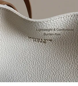 Detail shot of premium white litchi grain leather texture on the tote handbag surface