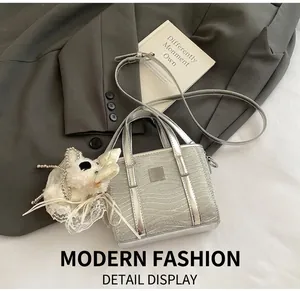 Detail of silver textured mini tote bag with cute plush puppy charm on a grey blazer