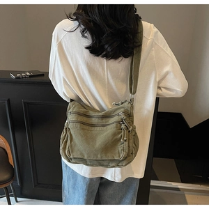 Detail of army green canvas crossbody bag with multi-zipper compartments and wide strap