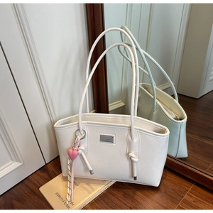 Detail of white pleated leather tote bag with silver plate and pink heart charm