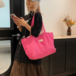 Gros plan d'un sac cabas rose vif avec motif à carreaux texturé et étiquette de marque tissée