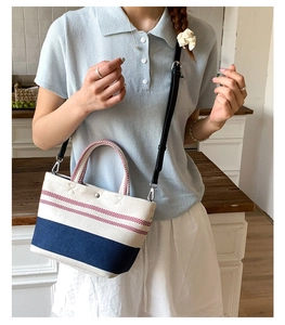 Detailed view of canvas tote with navy stripes and detachable strap on model