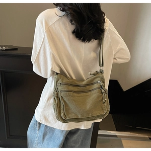 Detail of army green canvas tote with two front zipper pockets on an adjustable shoulder strap