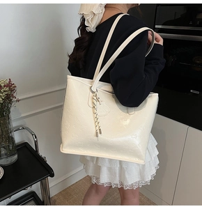 Détail du grand sac cabas crème avec motifs d'ours en relief et pendentif tressé