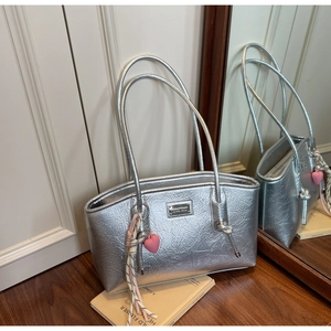 Detail of silver metallic tote bag with pleated texture and pink heart charm accessory