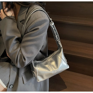 Dettaglio della borsa hobo argento metallizzato con tracolla regolabile su un blazer
