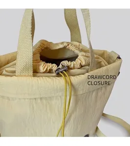 Detail of yellow canvas bucket bag showing drawstring closure and metal slider buckle