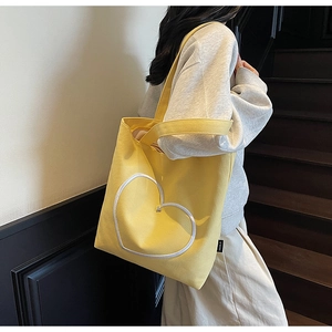 Détail du cabas en toile jaune avec contour de grand cœur blanc sur le côté du sac