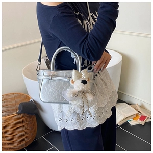 Détail du sac seau argenté avec texture plissée et charmant pendentif chien en peluche