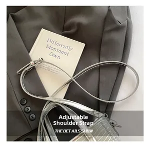 Detail of adjustable silver shoulder strap buckle on shiny metallic bucket bag