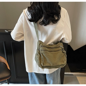 Detail view of large army green canvas crossbody bag with multiple front zipper pockets