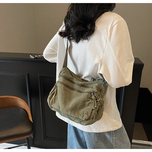Detail view of army green multi-pocket canvas crossbody bag showing functional zippers