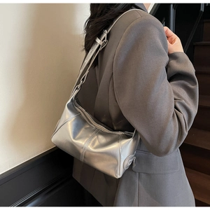Dettaglio della borsa hobo argento metallizzato indossata da una modella in blazer grigio