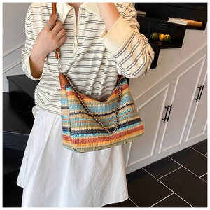 Detail of colorful woven shoulder bag with vibrant stripes and brown leather straps