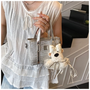 Detail of silver metallic bucket bag with cracked texture and plush bear charm